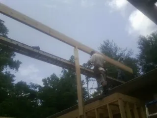 Carpenter setting a ridge beam over a new addition frame — Ice Dam Removal by Roofing Brothers in Newburg
