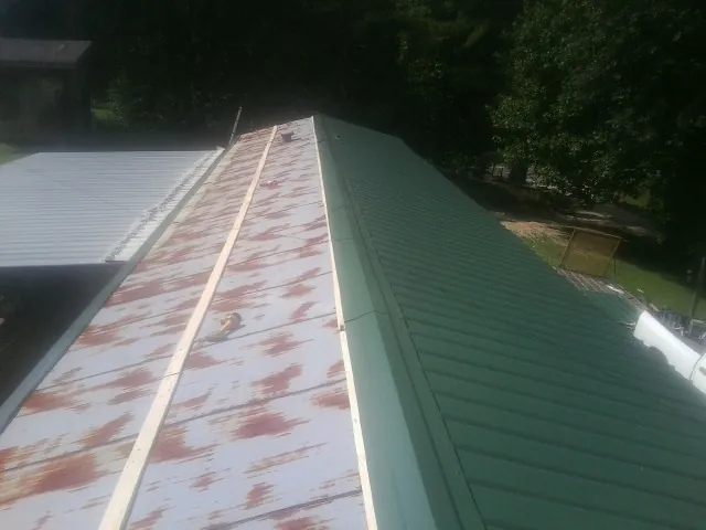 Old rusted panels beside newly installed green metal roofing — Wind Damage Roof Repair by Roofing Brothers in Newburg