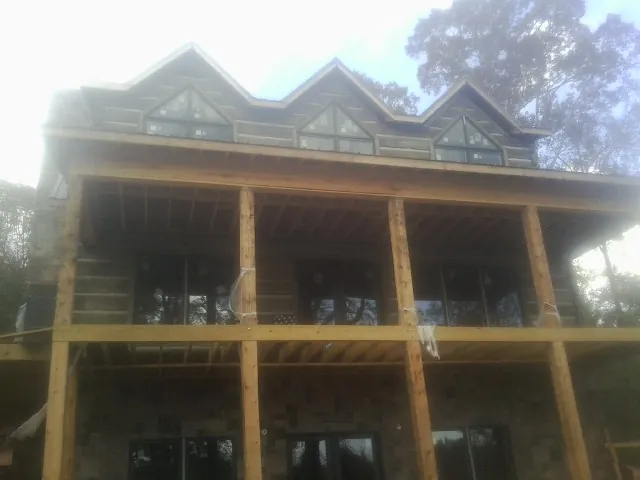 Dormers and porch framing on a large log home under construction — Roof Coating work by our crew in Newburg