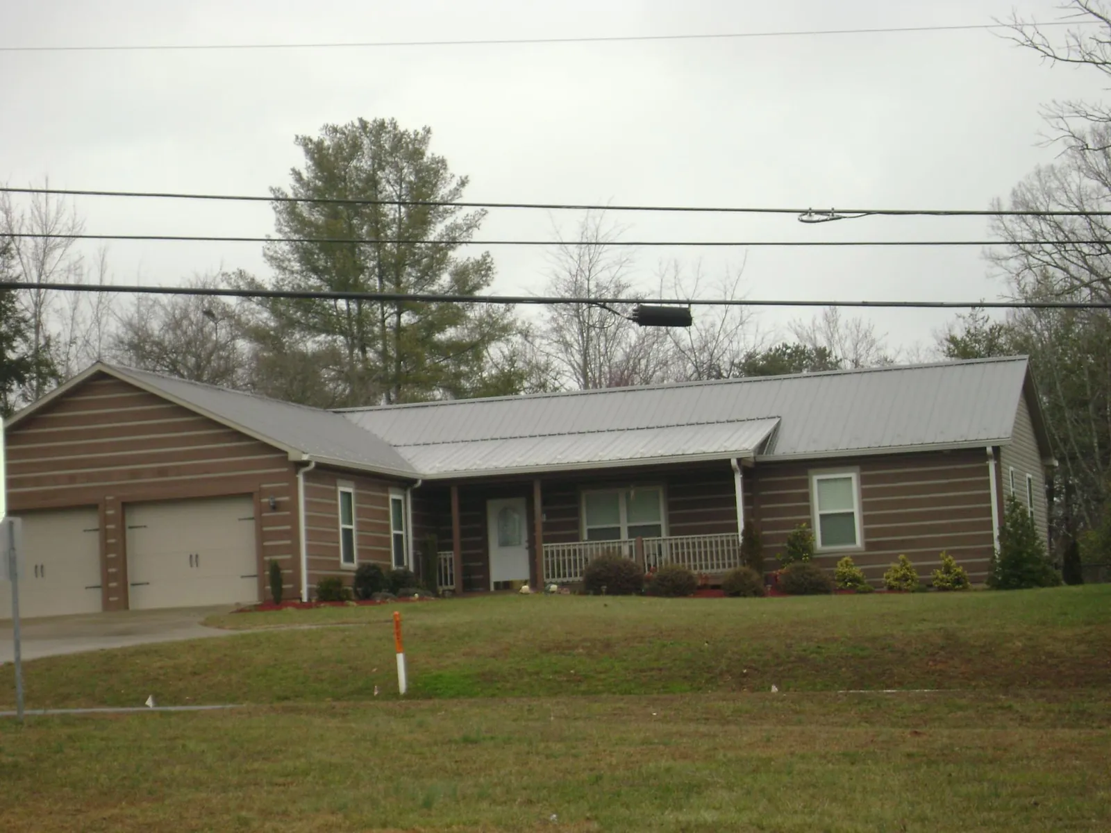 Gray metal roof on a log sided ranch home with a front porch in Newburg